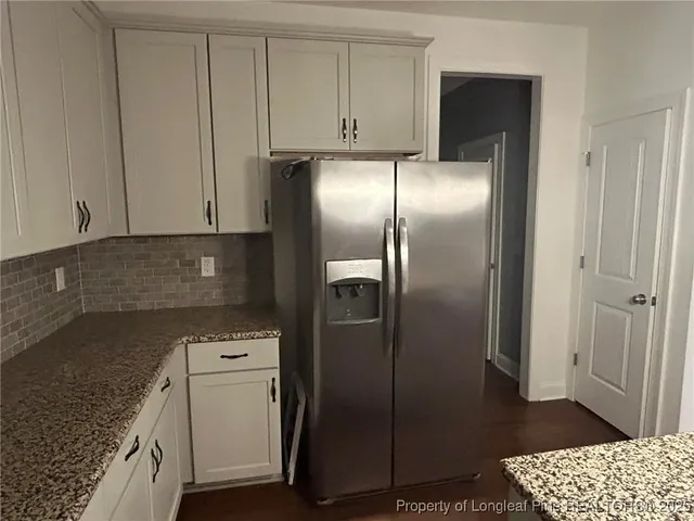 a kitchen with metallic refrigerator freezer and a granite counter tops