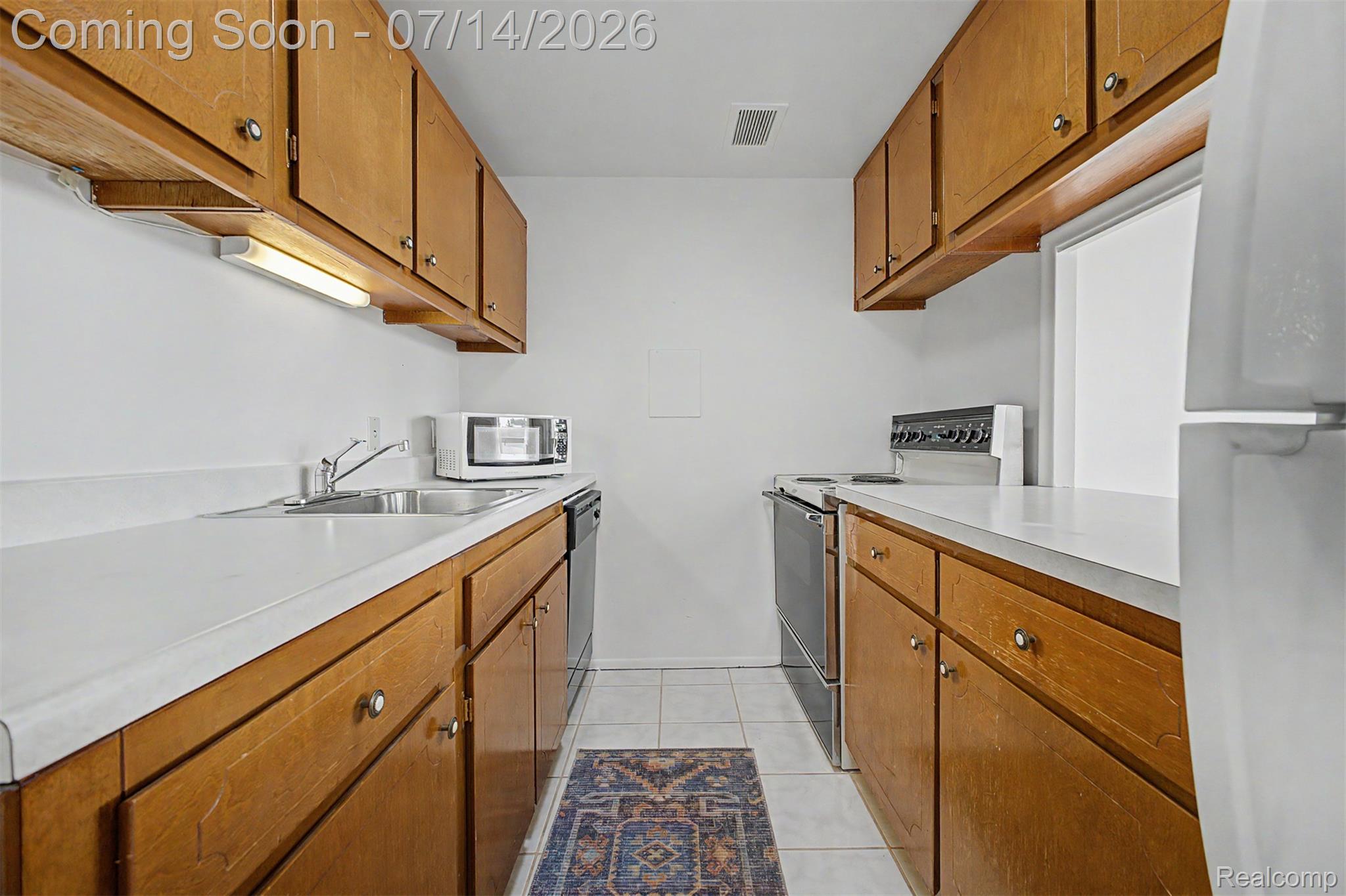 22700 Garrison Street, Unit 707 Dearborn, MI 48124 - Photo 8 of 22 Galley kitchen featuring wood cabinetry, white countertops, a stainless steel sink, and white tile flooring