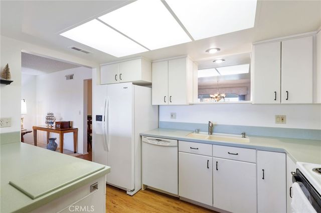 a kitchen with a refrigerator a sink and dishwasher with wooden cabinets