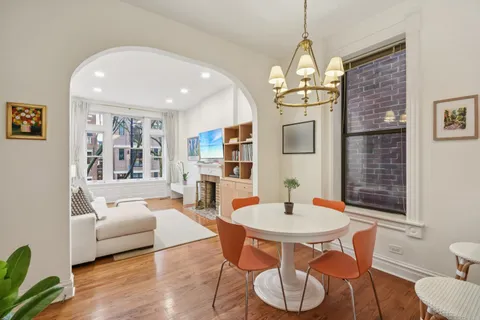 a dining room with wooden floor a chandelier a glass table and chairs