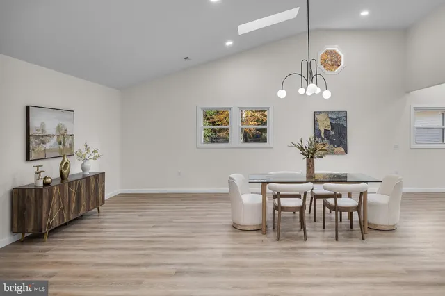 a open kitchen with stainless steel appliances granite countertop a stove top oven a refrigerator a dining table and chairs with wooden floor