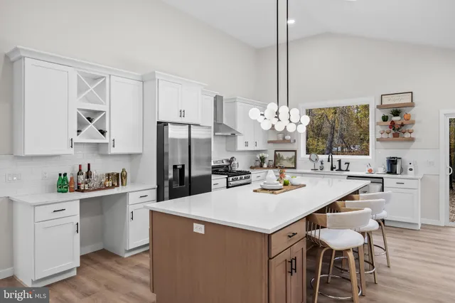 a large white kitchen with a large island oven a sink dishwasher a dining table and chairs with wooden floor