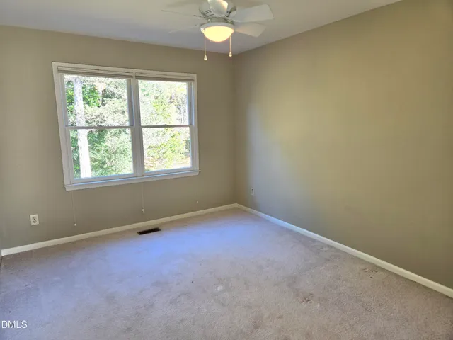 an empty room with windows and chandelier fan