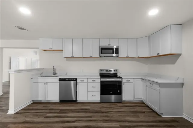 a kitchen with stainless steel appliances a sink dishwasher a stove top oven a refrigerator and cabinets