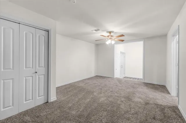 a view of an empty room with a chandelier fan