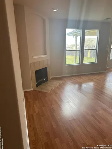an empty room with wooden floor fireplace and windows