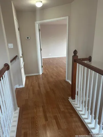 a view of a hallway with wooden floor and stairs