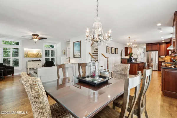 a kitchen with stainless steel appliances granite countertop a stove top oven a sink a dining table and chairs with wooden floor