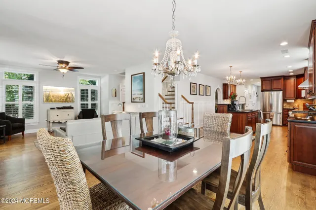 a kitchen with stainless steel appliances granite countertop a stove top oven a sink a dining table and chairs with wooden floor