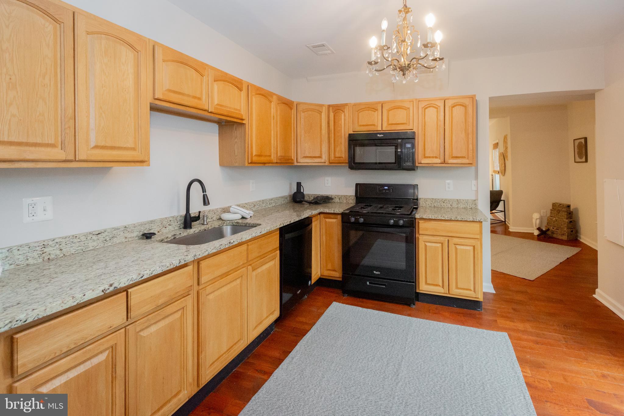 2129 Channing Street Northeast Washington, DC 20018 - Photo 11 of 37 a kitchen with stainless steel appliances granite countertop a sink dishwasher a stove top oven a refrigerator with grey cabinets and wooden floor