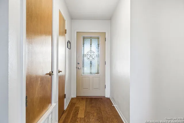 a view of a hallway with wooden floor and a bathroom