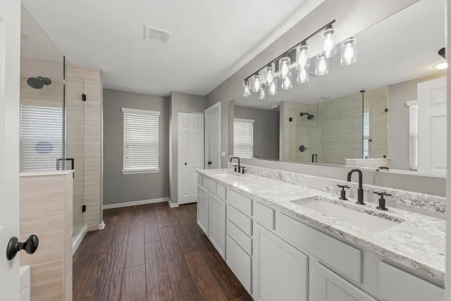 a spacious bathroom with a double vanity sink mirror and shower