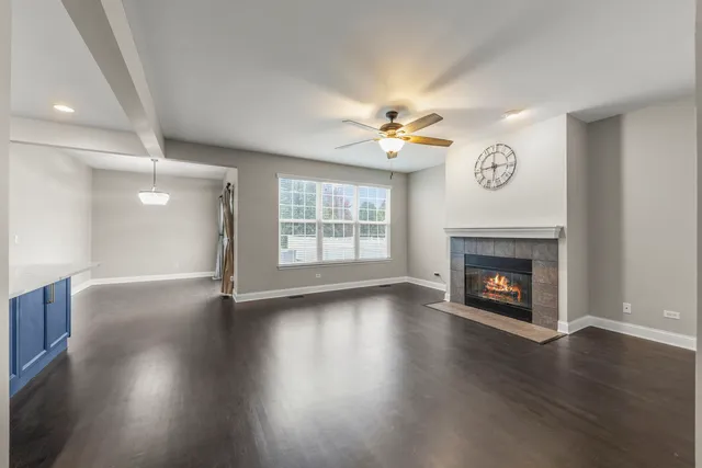 an empty room with windows a fireplace and wooden floor