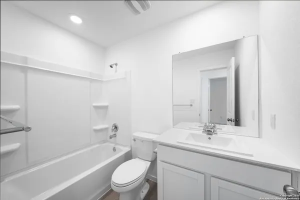 a bathroom with a toilet a sink a mirror a bathtub and vanity