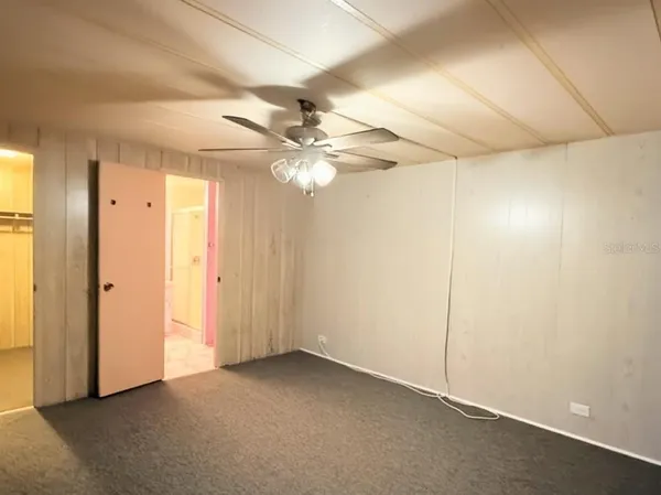 an empty room with a chandelier fan and closet