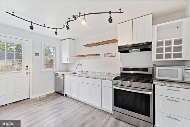 a kitchen with stainless steel appliances white cabinets and a stove top oven