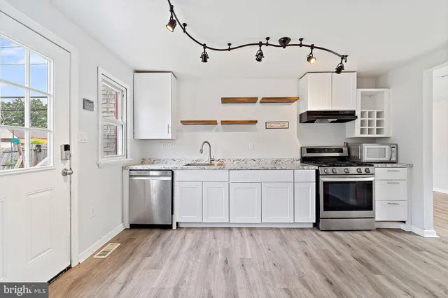 a kitchen with granite countertop a sink cabinets stainless steel appliances and a window