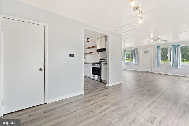 an empty room with wooden floor and windows