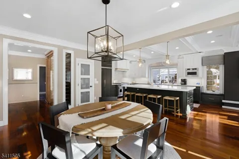 a large kitchen with granite countertop a stove a sink dishwasher a dining table and chairs with wooden floor