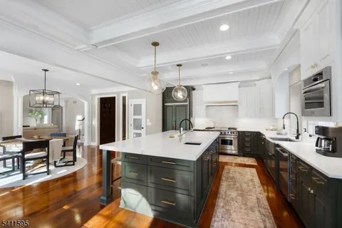 a kitchen with stainless steel appliances granite countertop a sink a stove and a wooden floors