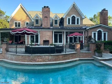 a view of a brick house with a big yard and large trees
