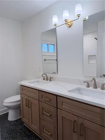 a bathroom with a granite countertop toilet sink and mirror