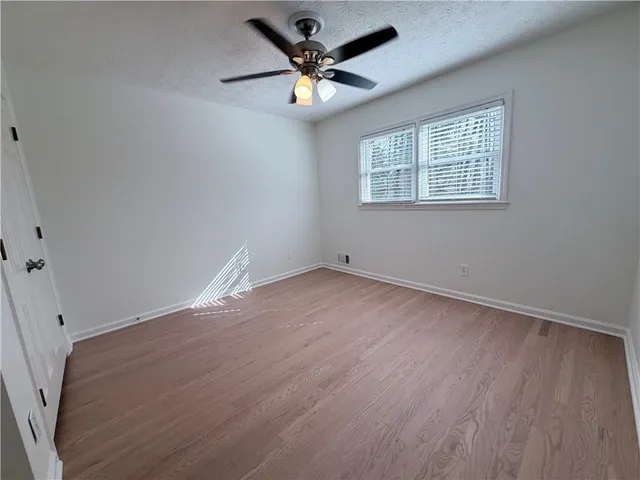 an empty room with wooden floor and ceiling fan