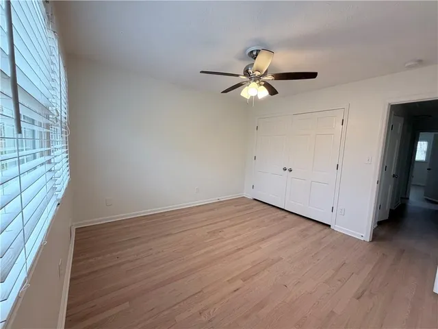 an empty room with wooden floor fan and windows