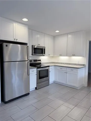 a kitchen with kitchen island granite countertop a refrigerator oven a sink and dishwasher