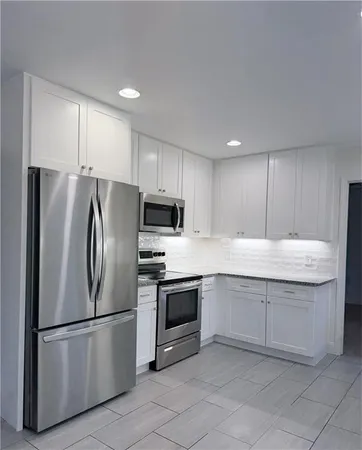 a kitchen with stainless steel appliances granite countertop a refrigerator a stove a sink and a microwave