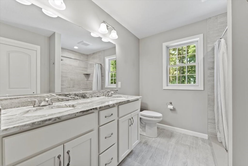 145 Barrington Drive Springfield, MA 01129 - Photo 26 of 42 a bathroom with a granite countertop double vanity sink a mirror and a toilet