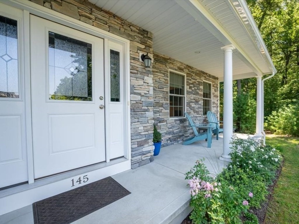 145 Barrington Drive Springfield, MA 01129 - Photo 4 of 42 front view of a house with a potted plant and a bench