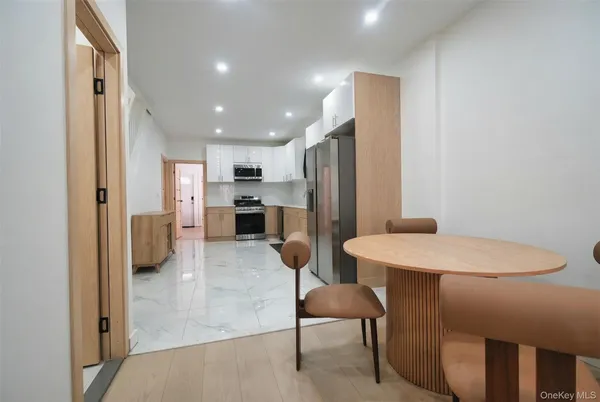 a kitchen with stainless steel appliances refrigerator dining table and chairs