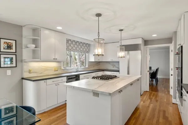 a kitchen with a stove a sink a refrigerator and chairs