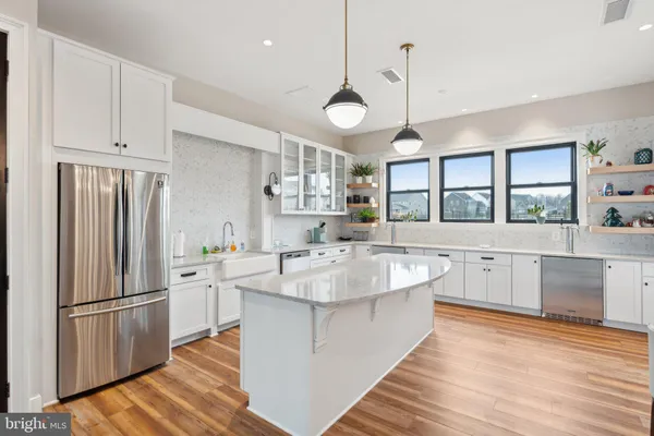 a large white kitchen with stainless steel appliances lots of counter space and a sink