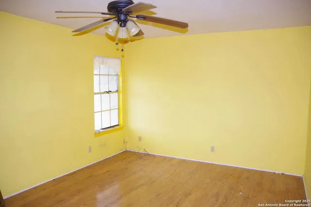 a view of empty room with wooden floor and fan