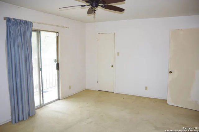 an empty room with a ceiling fan and a window