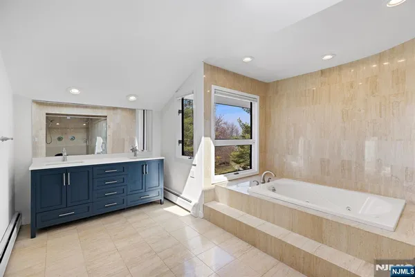 a spacious bathroom with a tub sink and mirror
