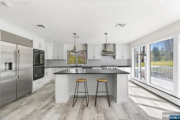 a kitchen with stainless steel appliances granite countertop a table chairs stove refrigerator and cabinets