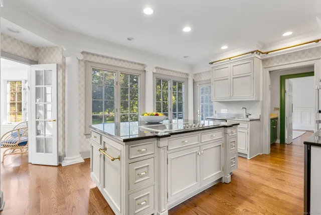 a kitchen with granite countertop a stove and white cabinets with wooden floor