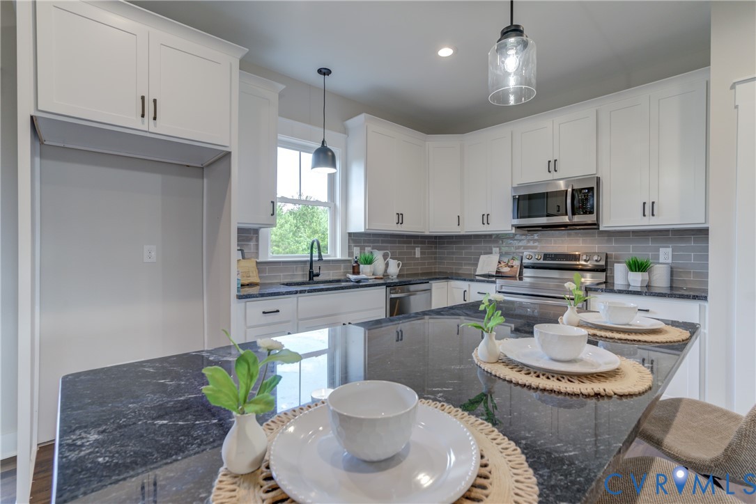 5306 St Pauls Church Road Goochland, VA 23063 - Photo 15 of 35 a kitchen with stainless steel appliances granite countertop a stove a sink a microwave a dining table and chairs