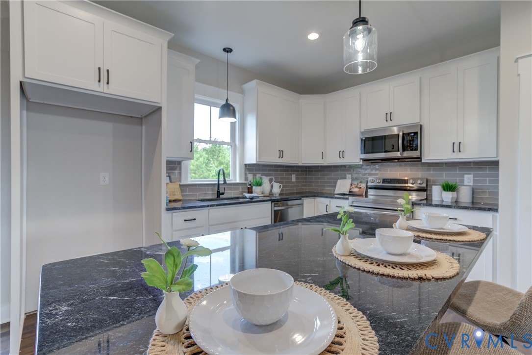5306 St Pauls Church Road Goochland, VA 23063 - Photo 17 of 35 a kitchen with stainless steel appliances granite countertop a stove a sink a microwave a dining table and chairs