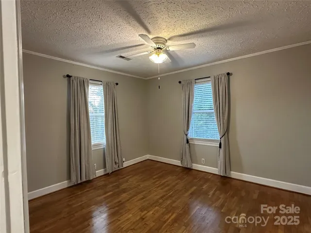 an empty room with wooden floor fan and windows