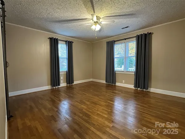 a view of an empty room with window and wooden floor
