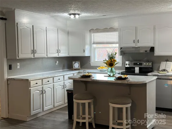 a kitchen with kitchen island granite countertop a sink cabinets and wooden floor