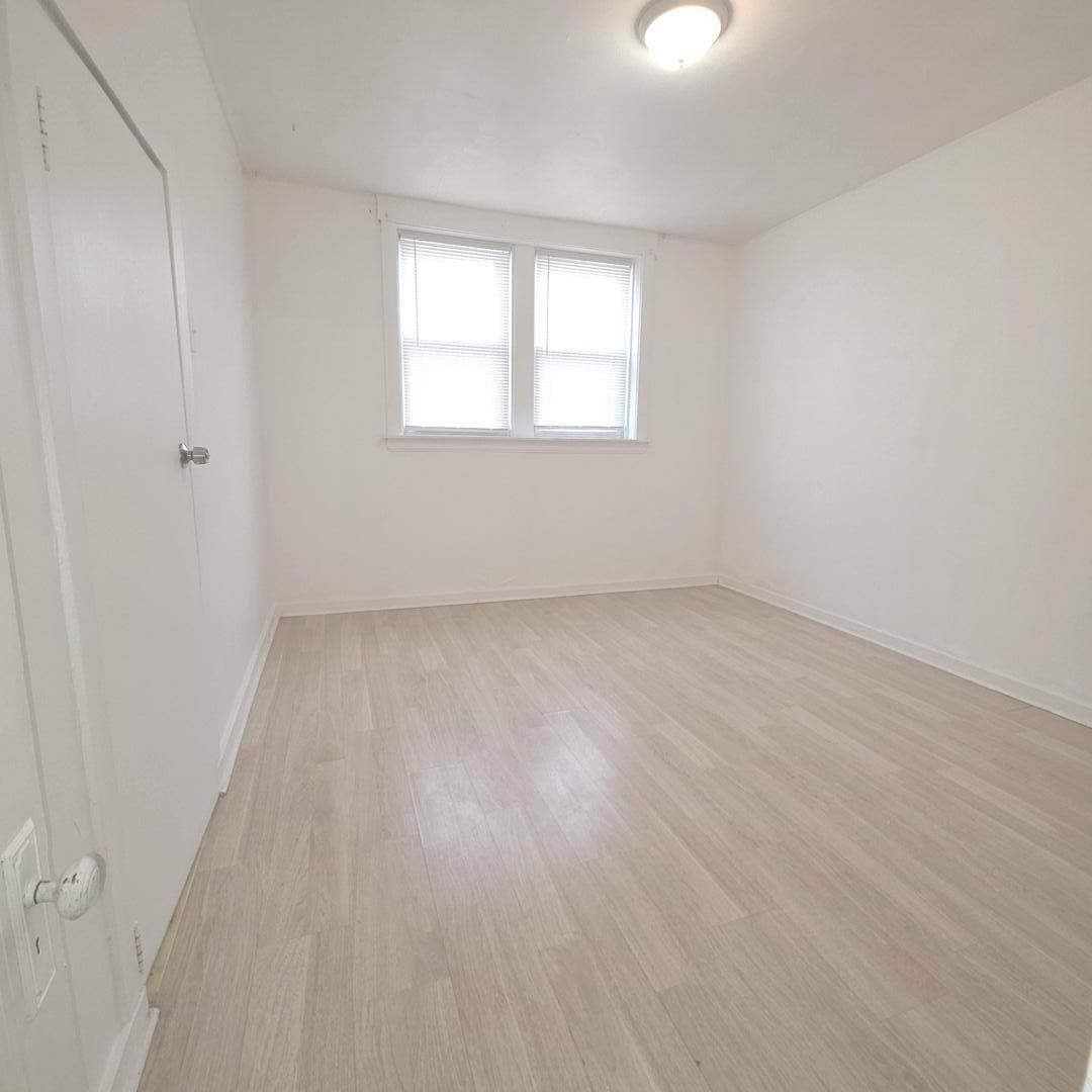 3301 West Potomac Avenue, Unit G Chicago, IL 60651 - Photo 9 of 18 an empty room with wooden floor and windows