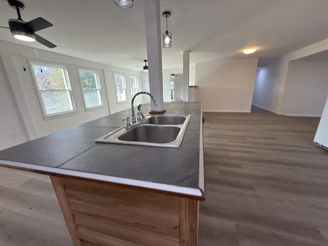 a view of an empty room with wooden floor and a ceiling fan