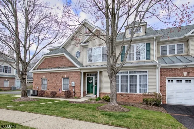 front view of a brick house with a yard and large trees