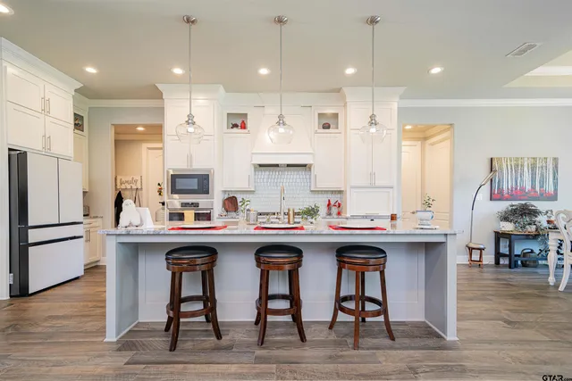 a kitchen with stainless steel appliances granite countertop a table chairs refrigerator and sink