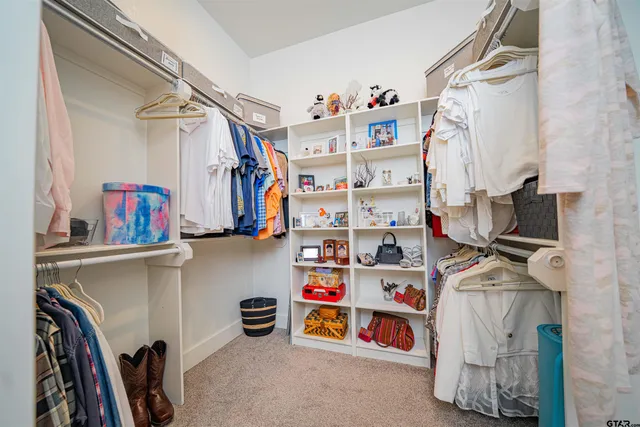 a view of walk in closet with clothes and shoes